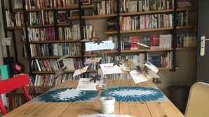 Una mesa de madera con una revista, un jarrón con flores artificiales y tarjetas de identificación.