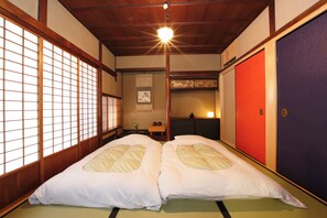 A traditional Japanese room with tatami flooring, a shoji screen, and a futon bed.