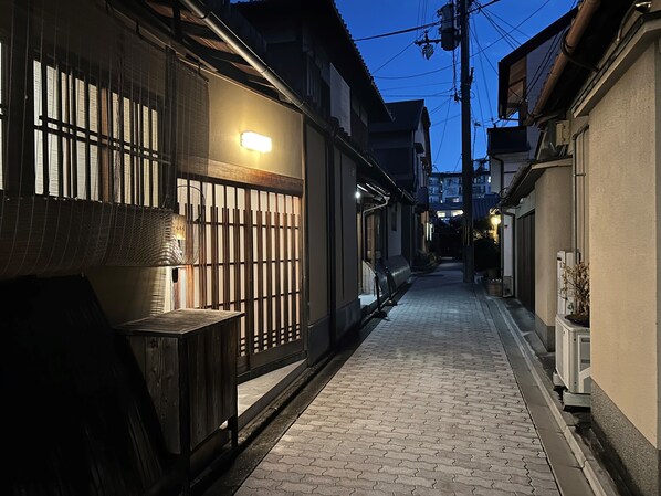 A narrow alleyway with traditional Japanese architecture, including wooden fences and tiled walls.