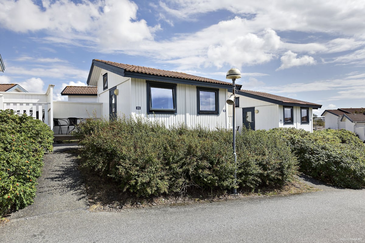 A single-story mobile home with a sloped roof, two windows, and a small porch area.