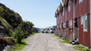 A gravel path leading to a row of red buildings with white trim, each with a small porch and flower boxes.