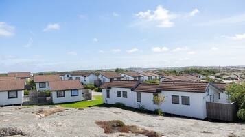 A row of white mobile homes with brown roofs, set against a clear sky.