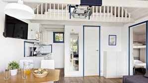 A compact apartment with a dining area, kitchenette, and a living space with a sofa and a TV.