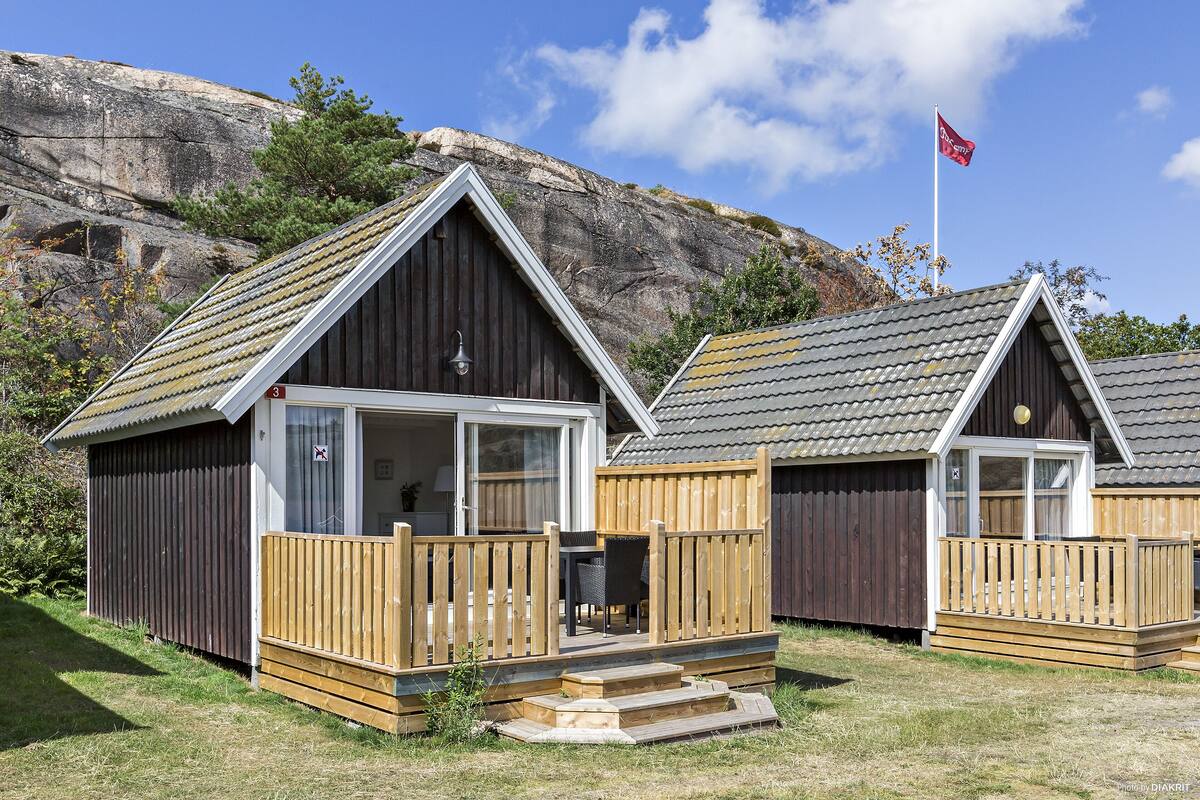 A wooden cabin with a balcony, a door, and a window.