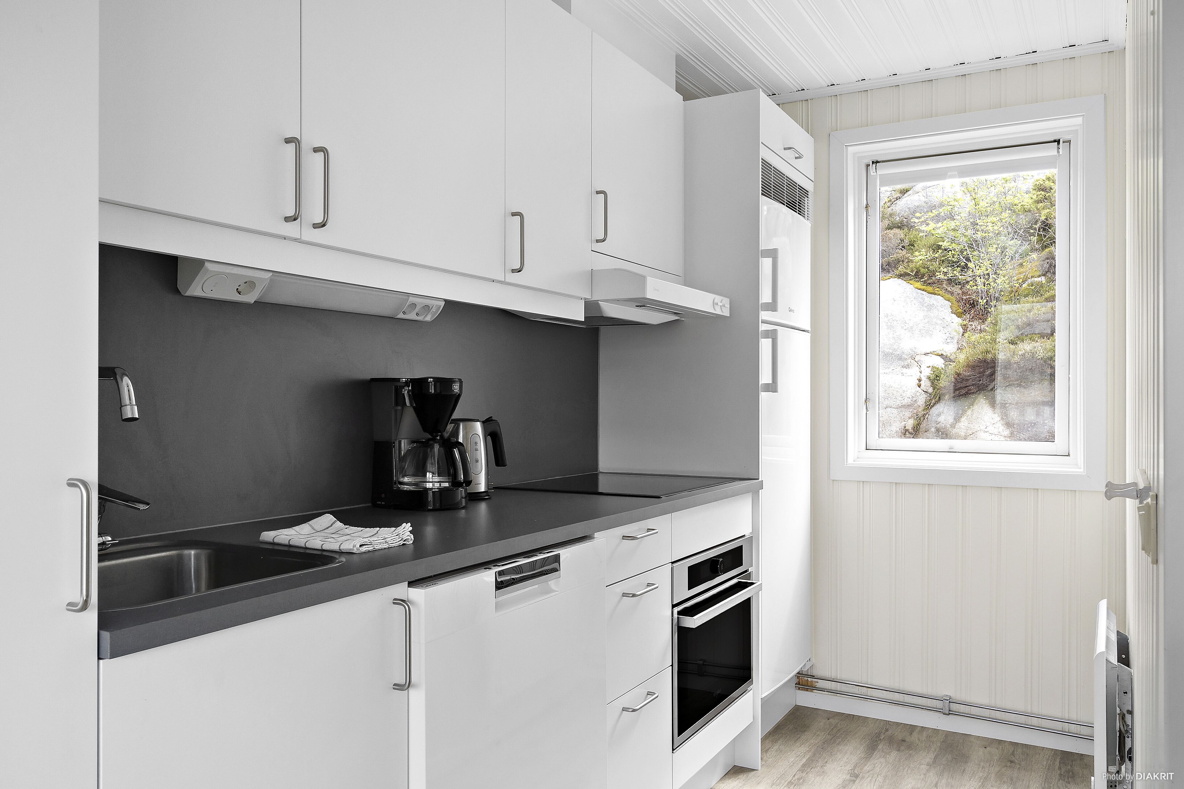 Een moderne keuken met witte kasten, een zwart aanrecht en een inbouwoven.