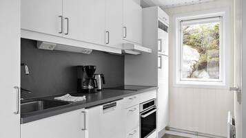 A modern kitchen with white cabinets, a black countertop, and a built-in oven.
