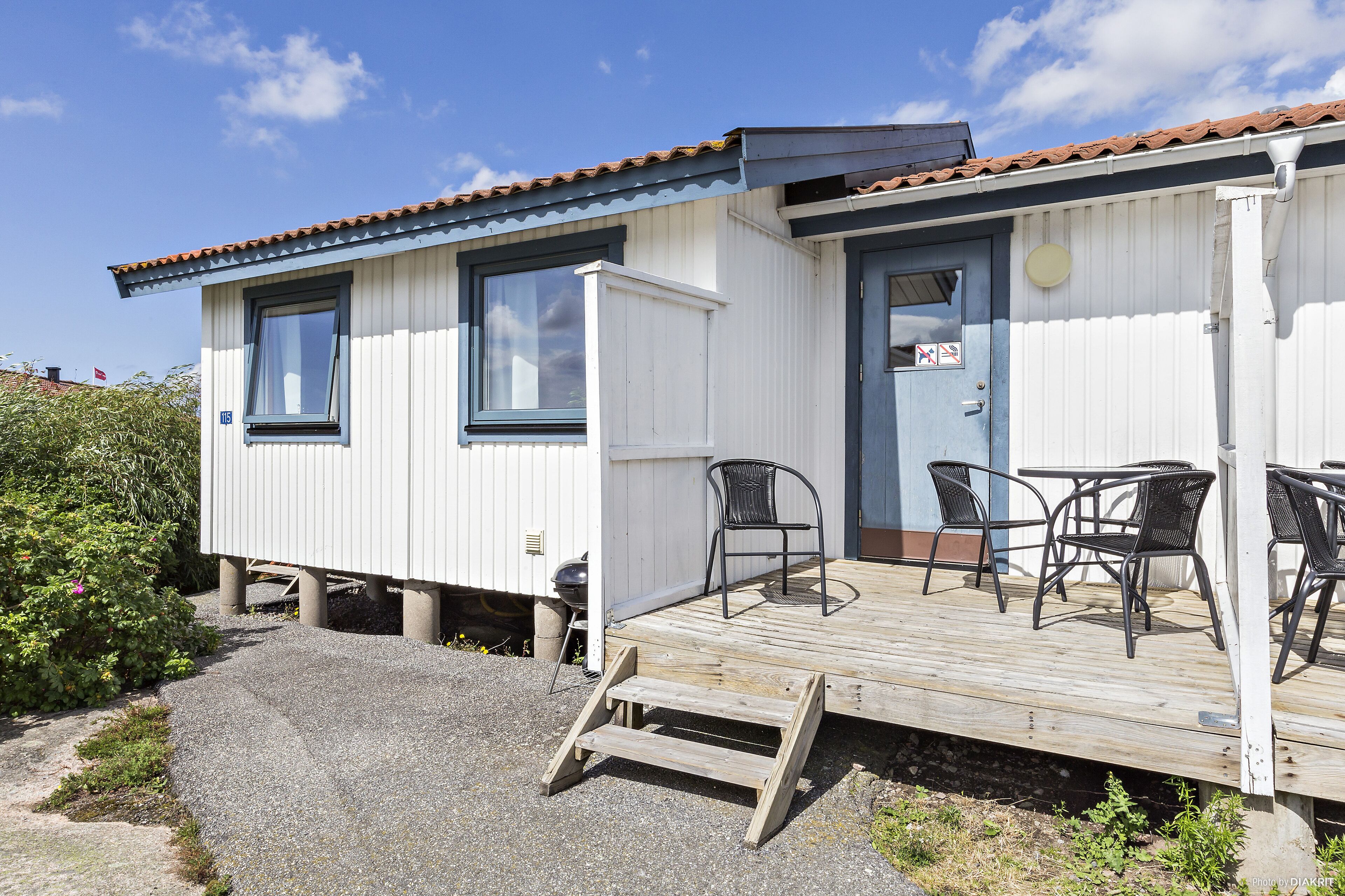 A small, single-story building with a wooden deck and outdoor seating.