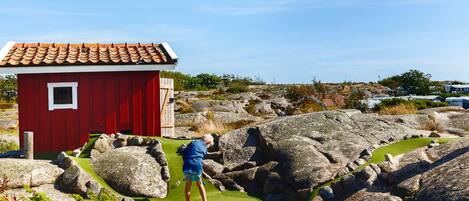 A red building with a tiled roof, surrounded by large rocks and greenery.