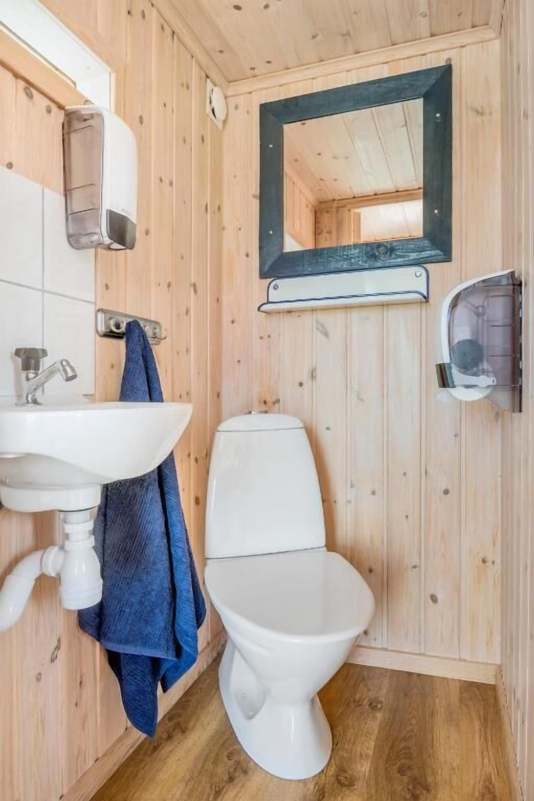 Un bany de fusta amb un lavabo, un vàter i un mirall blancs.