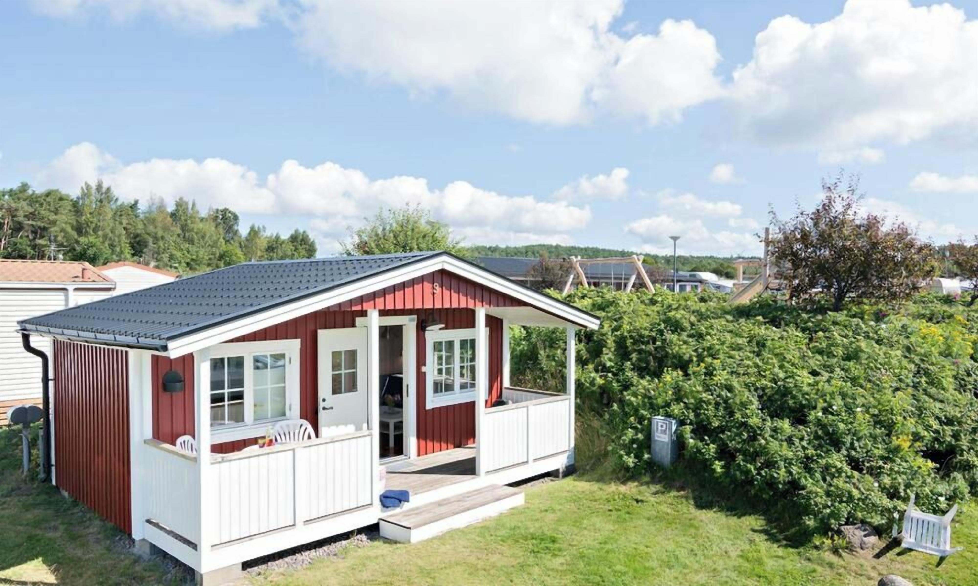 A small, single-story cabin with a porch and a covered outdoor seating area.