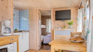A compact room with a kitchenette, a bed, a television, and a dining area. - First Camp Kärradal (Varberg)