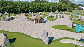 A miniature golf course with a paved path, green grass, and various obstacles. - First Camp Kärradal (Varberg)