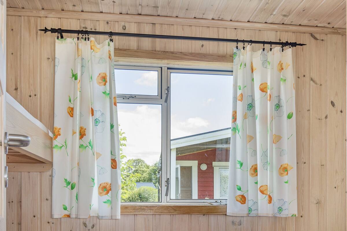 Una habitación con paneles de madera, una cama, una ventana con cortinas y vista a un edificio.