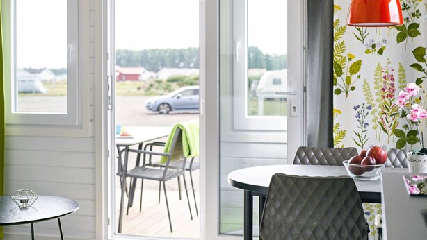 A dining area with a table, chairs, and a bowl of fruit. - First Camp Kärradal (Varberg)