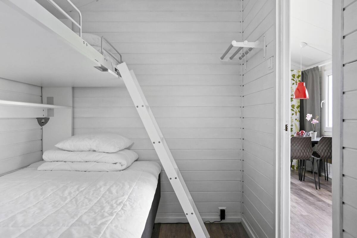 Una habitación con literas, una escalera, un escritorio y una silla.