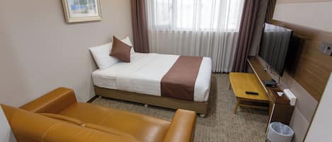 Quarto de hotel com uma cama, um sofá, uma escrivaninha, uma televisão e um quadro na parede.