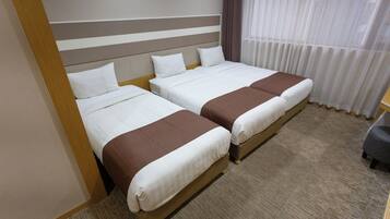 Habitación de hotel con dos camas, cabecera de madera, piso alfombrado y una ventana con cortinas.