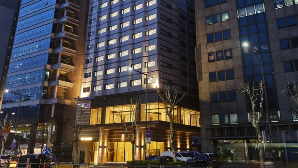 Un hotel moderno de gran altura con varios pisos, amplias ventanas y una entrada destacada.