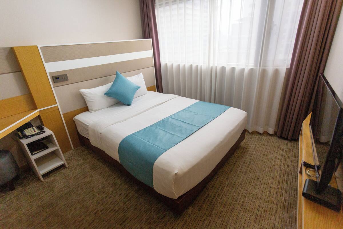 Une chambre d’hôtel avec un lit, une télévision, un bureau et une chaise.
