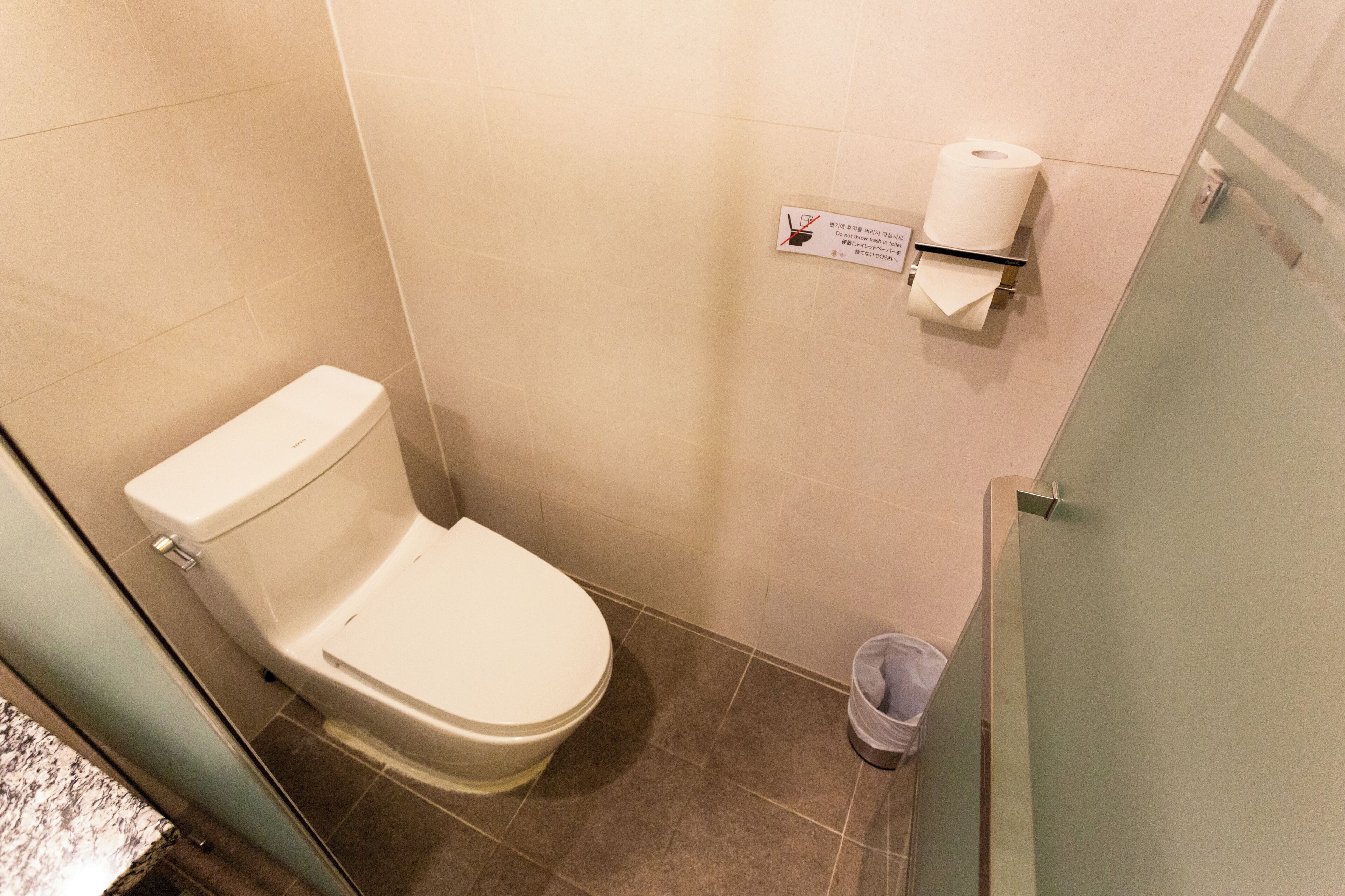 Et lille, moderne badeværelse med toilet, skraldespand og toiletpapirholder.