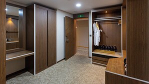 Una habitación de hotel con un armario de madera, un espejo, un perchero y un zapatero.