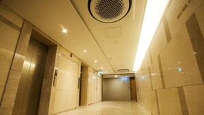 Un área de ascensor moderna con suelo de mármol, una lámpara de techo y una puerta con un número de teléfono.