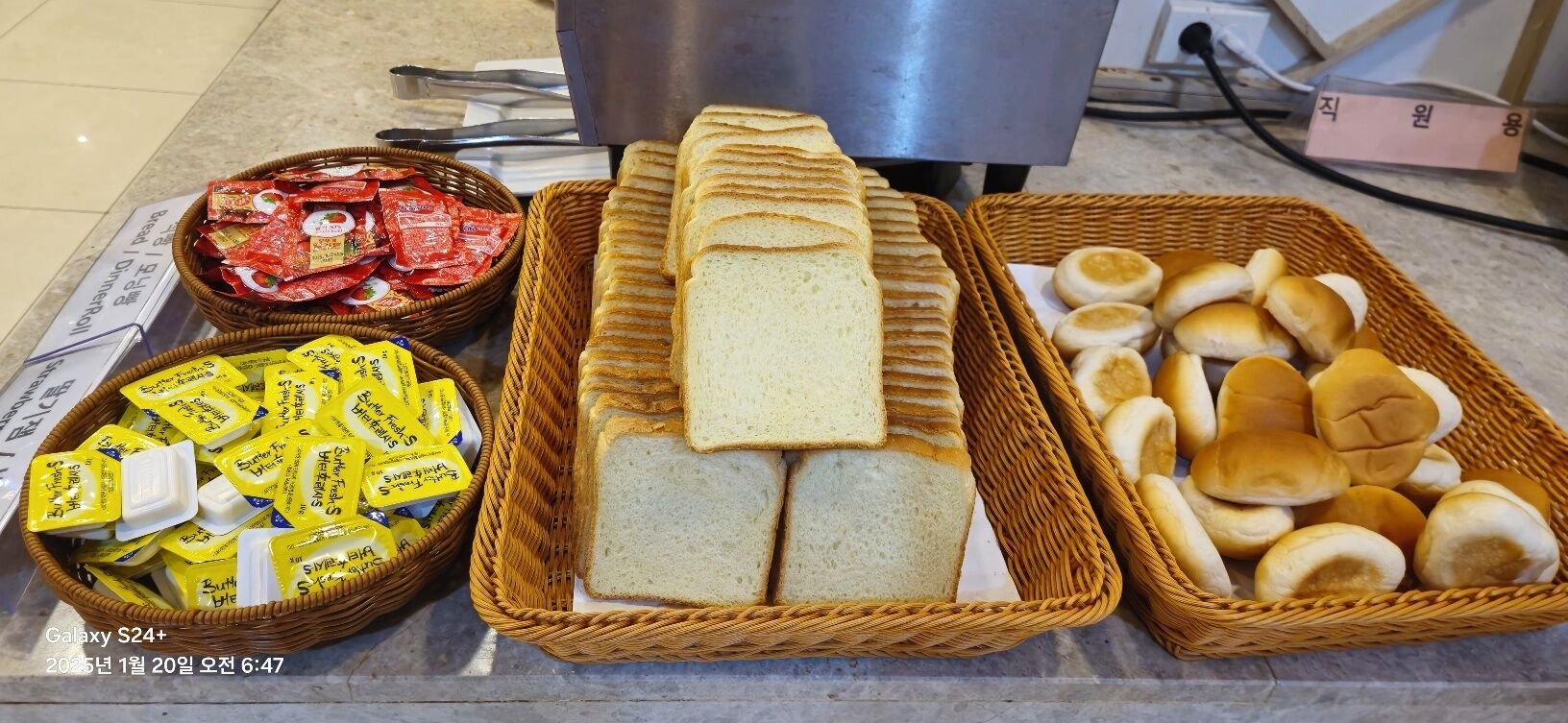 Une table de buffet proposant divers aliments, notamment du pain, des petits pains et des en-cas emballés.