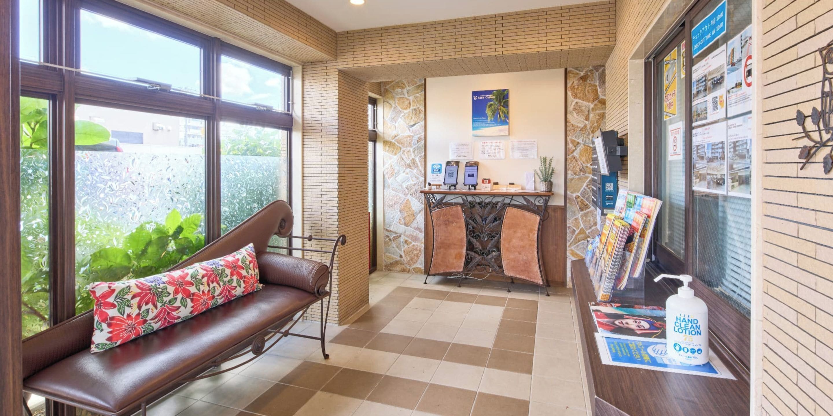 A reception area with a brown leather sofa, a stone wall, and a counter with hand sanitizer.