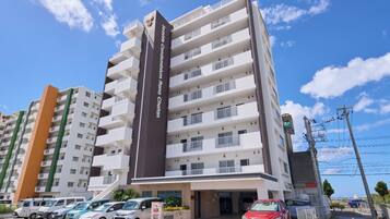 A multi-story residential building with balconies and a prominent vertical sign.