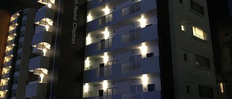 A multi-story hotel with illuminated balconies and a ground-level entrance.