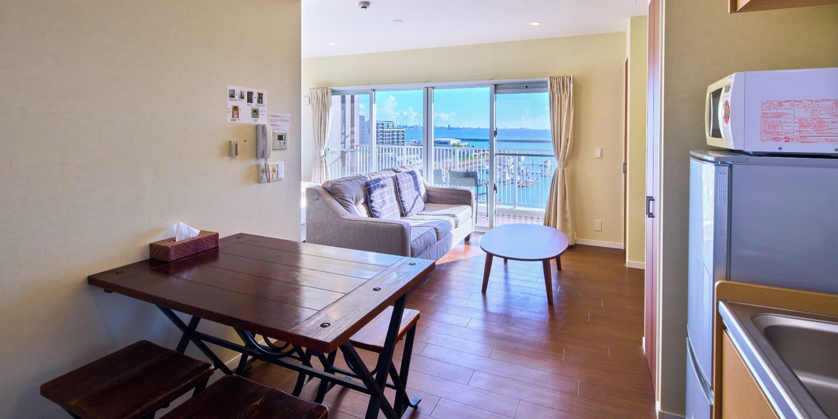 A compact living space with a dining table, a sofa, a small round table, and a kitchen area with a microwave.