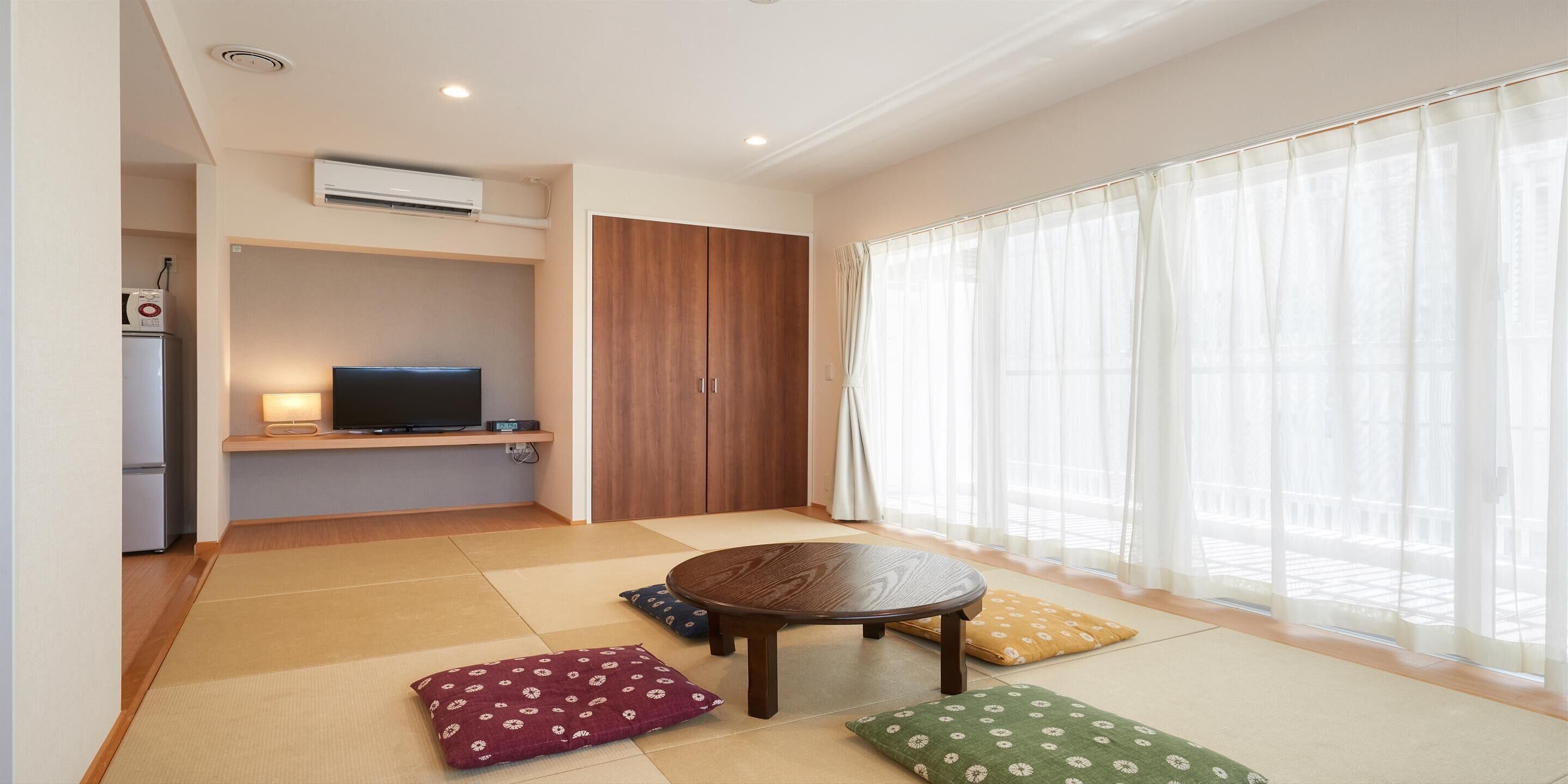 Una sala de estar moderna con esteras de tatami, un televisor y un armario de madera.