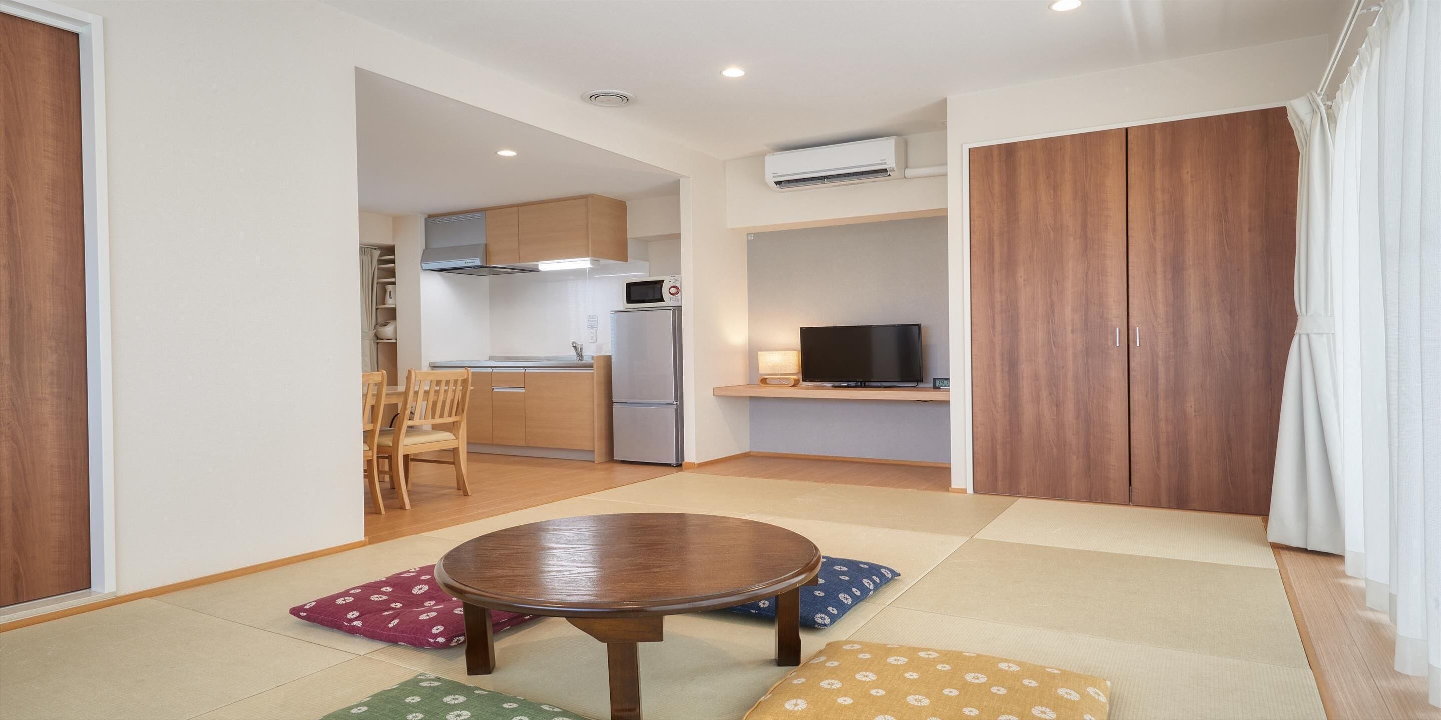 A compact living space with a dining area, kitchenette, and a TV.