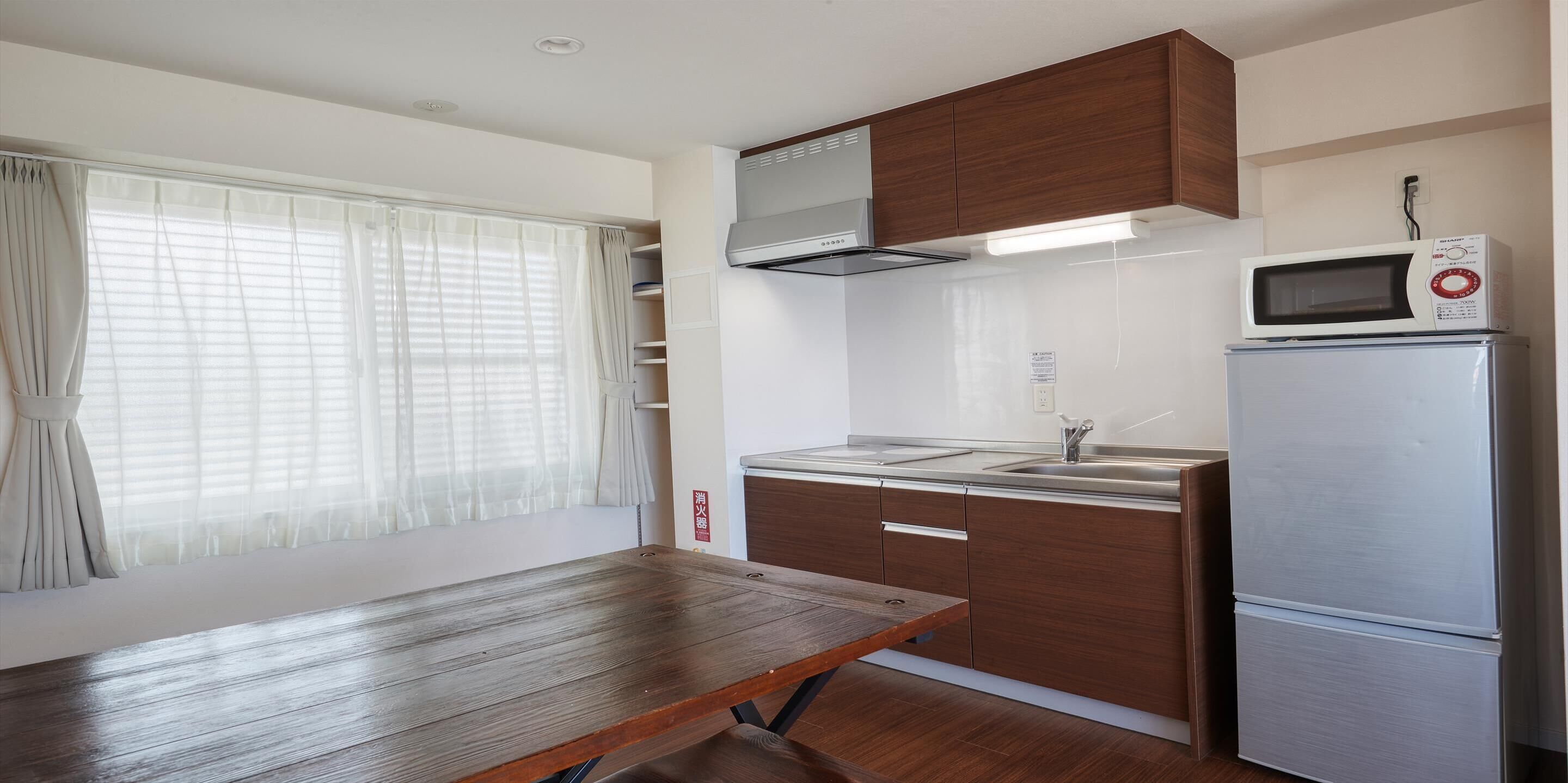 A compact kitchen with a wooden table, a built-in microwave, and a refrigerator.