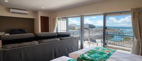 Habitación de hotel con balcón, sofá, cama y televisión.