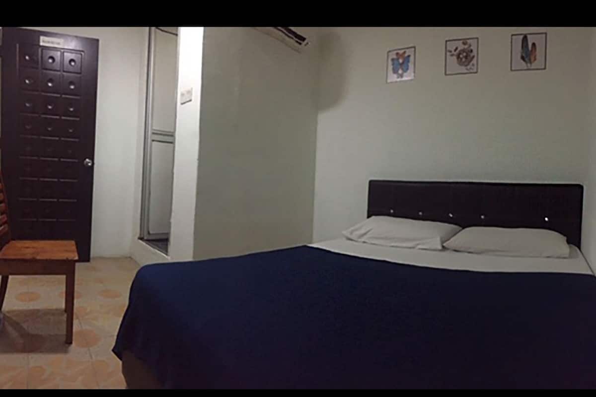 A bedroom with a bed, a chair, and a door.