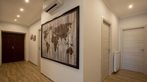 A hallway with wooden flooring, a large world map artwork, a door, and a radiator. - Vatican City Relais (Rome)