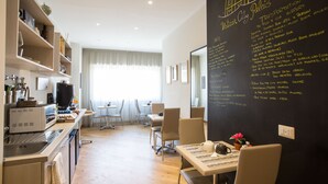 A modern hotel room with a kitchen area, dining space, and a blackboard with transportation information. - Vatican City Relais (Rome)