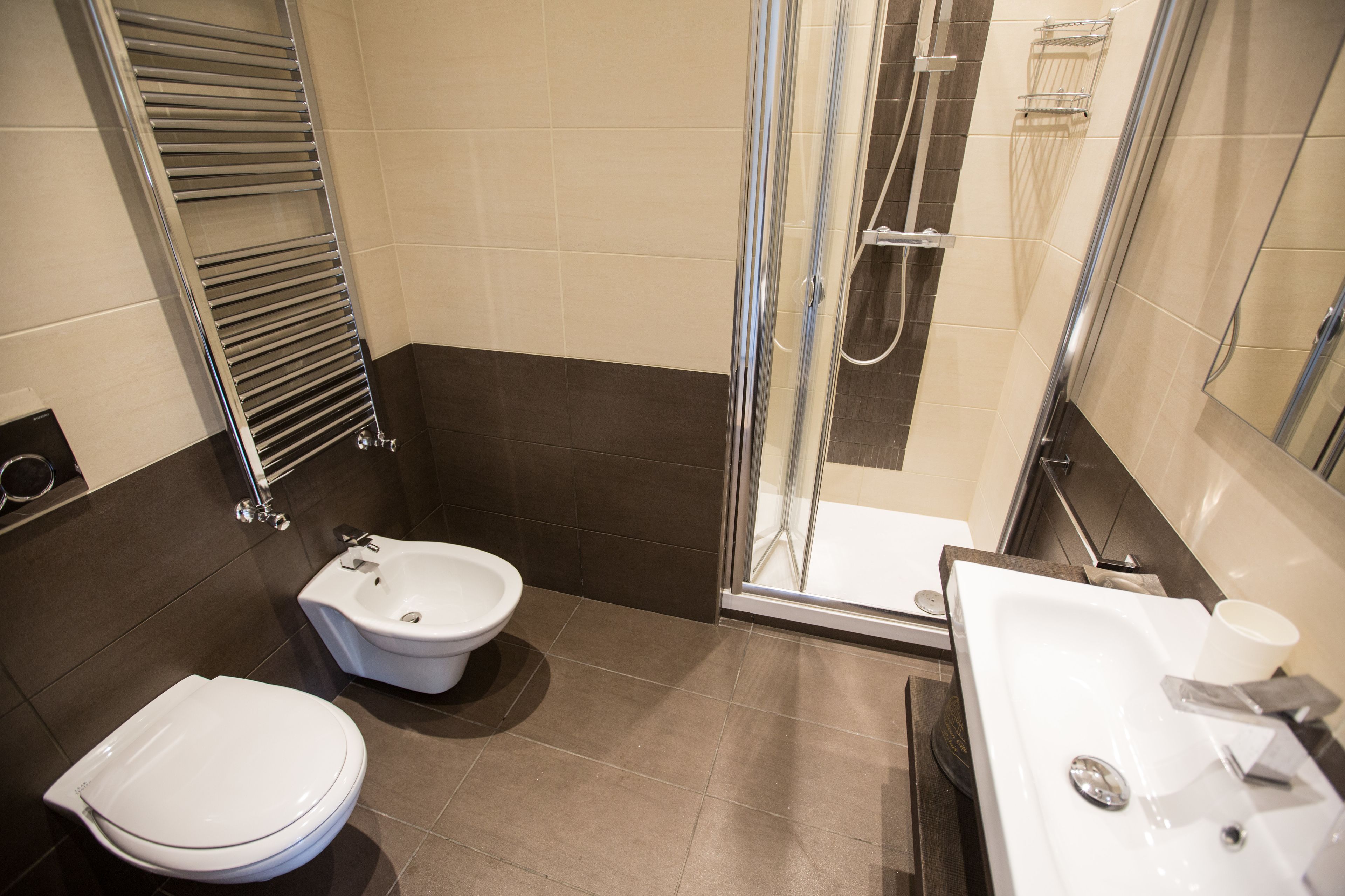 A modern bathroom with a toilet, bidet, shower, and sink.