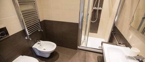 A modern bathroom with a toilet, bidet, shower, and sink.