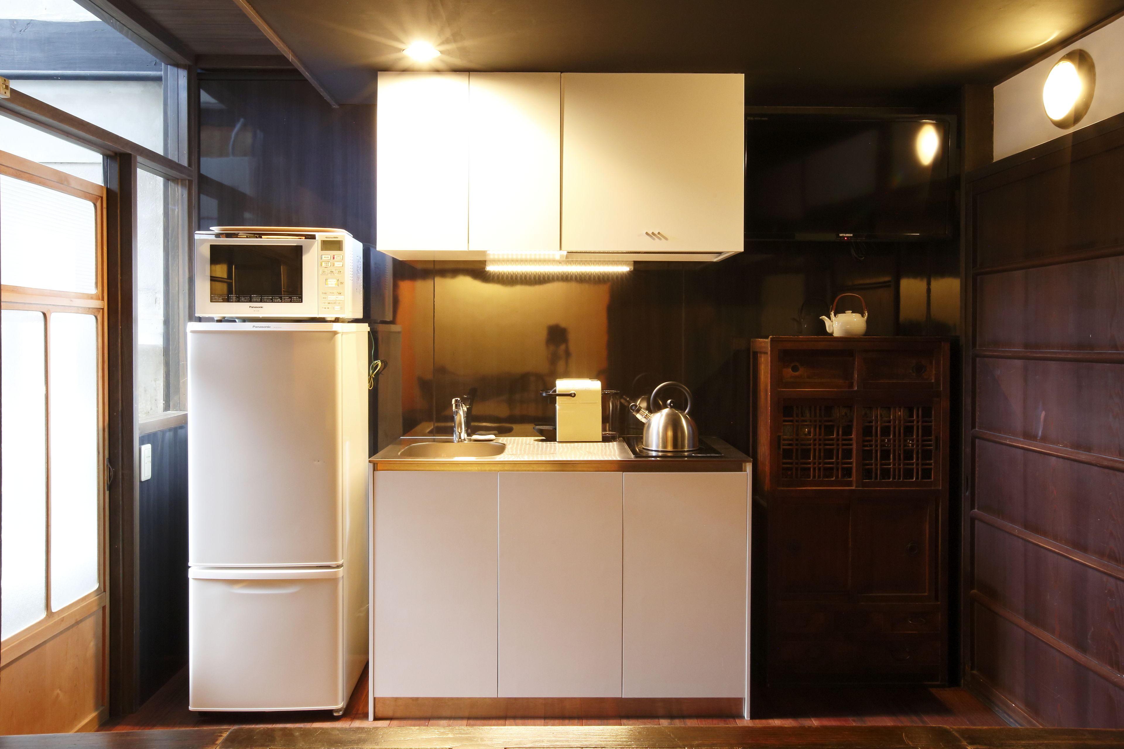 A compact kitchen with a refrigerator, microwave, sink, and wooden cabinets.