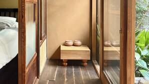 A traditional Japanese room with tatami flooring, a low wooden bench with ceramic bowls, and sliding doors leading to a garden. - Shimoza-an Kamanza-Tei (Kyoto)
