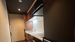 A modern kitchen with dark cabinetry, a stainless steel countertop, and a built-in oven. - Miyaki-tei (Kyoto)