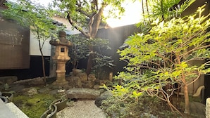 A traditional Japanese garden with a stone lantern, rock formations, and various plants. - Miyaki-tei (Kyoto)