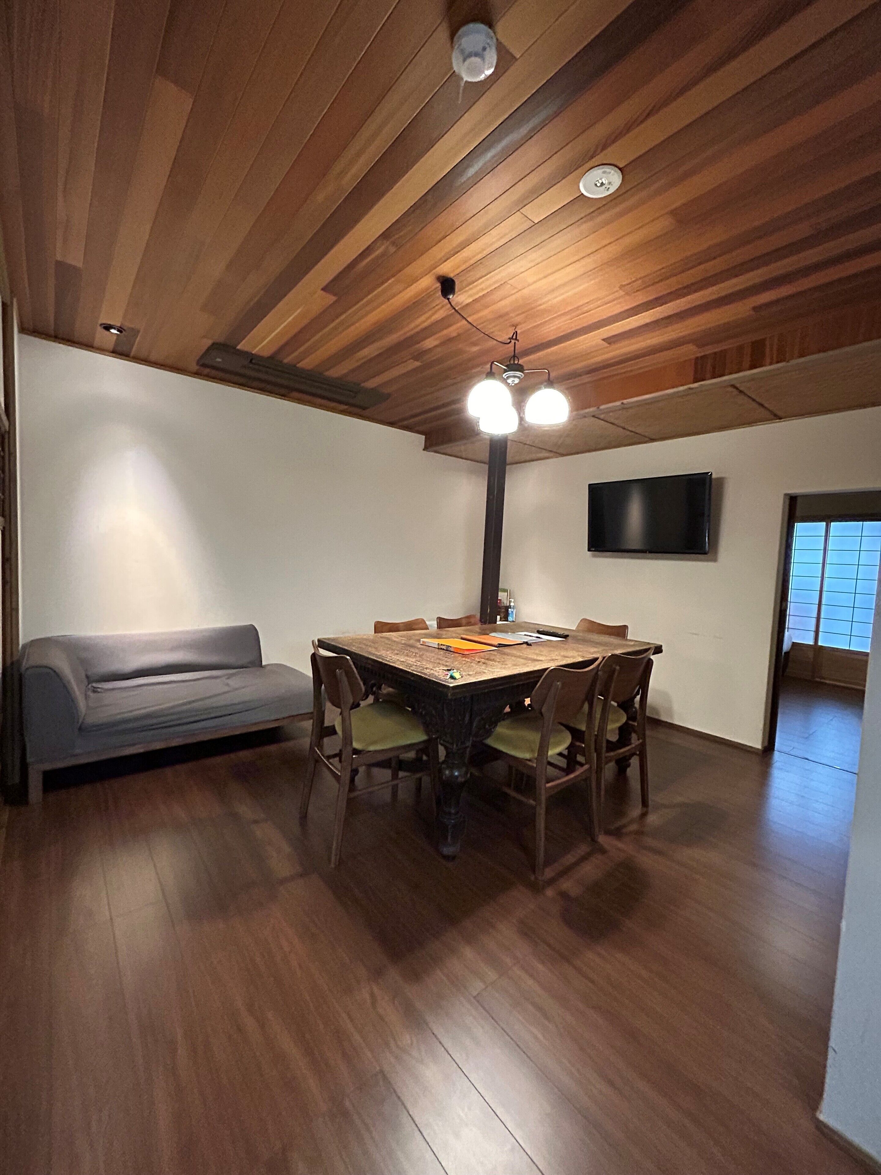 Un comedor con una mesa de madera, sillas y un sofá gris.