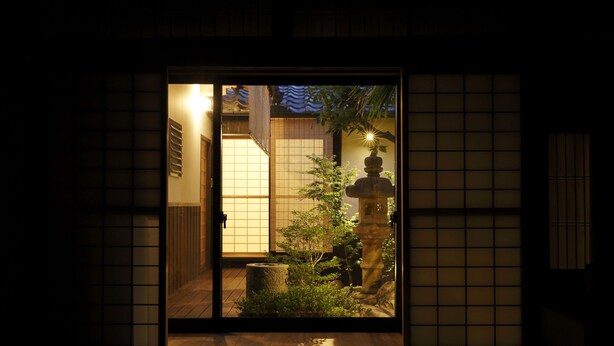 A traditional Japanese room with tatami flooring, a shoji screen door, and a small garden area with a stone lantern and plants. - Miyaki-tei (Kyoto)