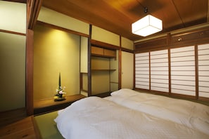 Una habitación tradicional japonesa con suelo de tatami, techo de madera bajo y puerta corredera de fusuma.