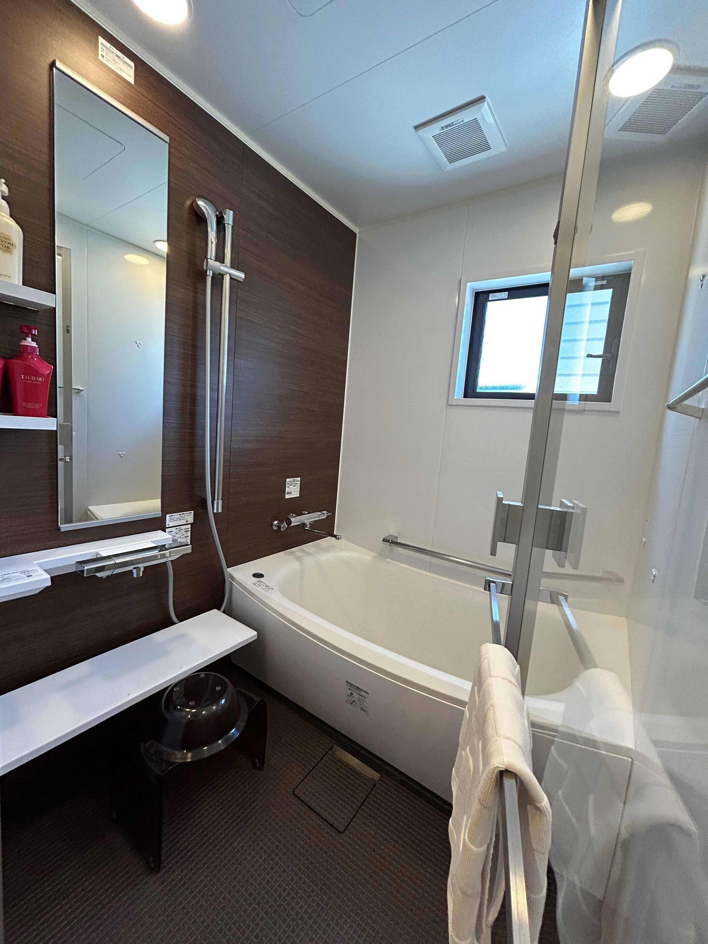 A modern bathroom with a large bathtub, a shower, a vanity with a mirror, and a window.