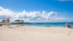 A beach with a lifeguard tower, clear blue sky, and calm sea. - Private Villa Gushikumui by Coldio Premium (Motobu)