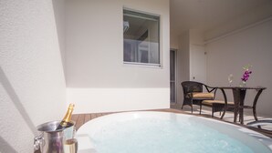 A hot tub with a champagne bottle and glass, a wicker chair, and a table with a vase of flowers. - Private Villa Gushikumui by Coldio Premium (Motobu)
